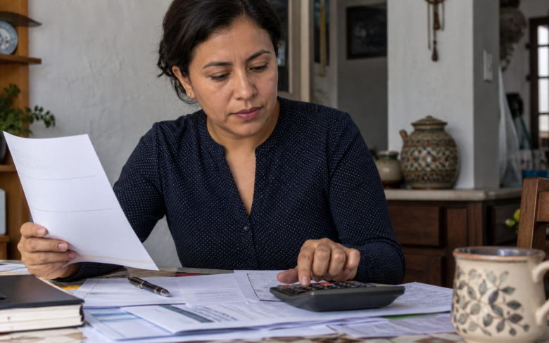 Persona compara contratos de crédito y una calculadora sobre una mesa de trabajo