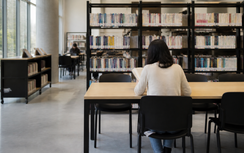 Biblioteca pública mexicana con estantes, mesas de estudio y una persona consultando una computadora